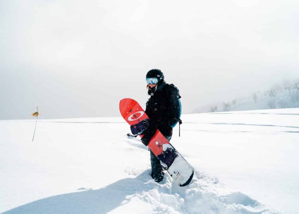 woman with snowboard in deep powder